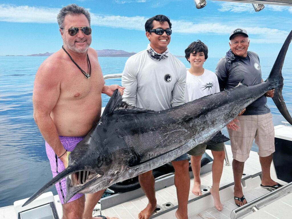 Anglers posing with a large marlin on a fishing charter in La Paz